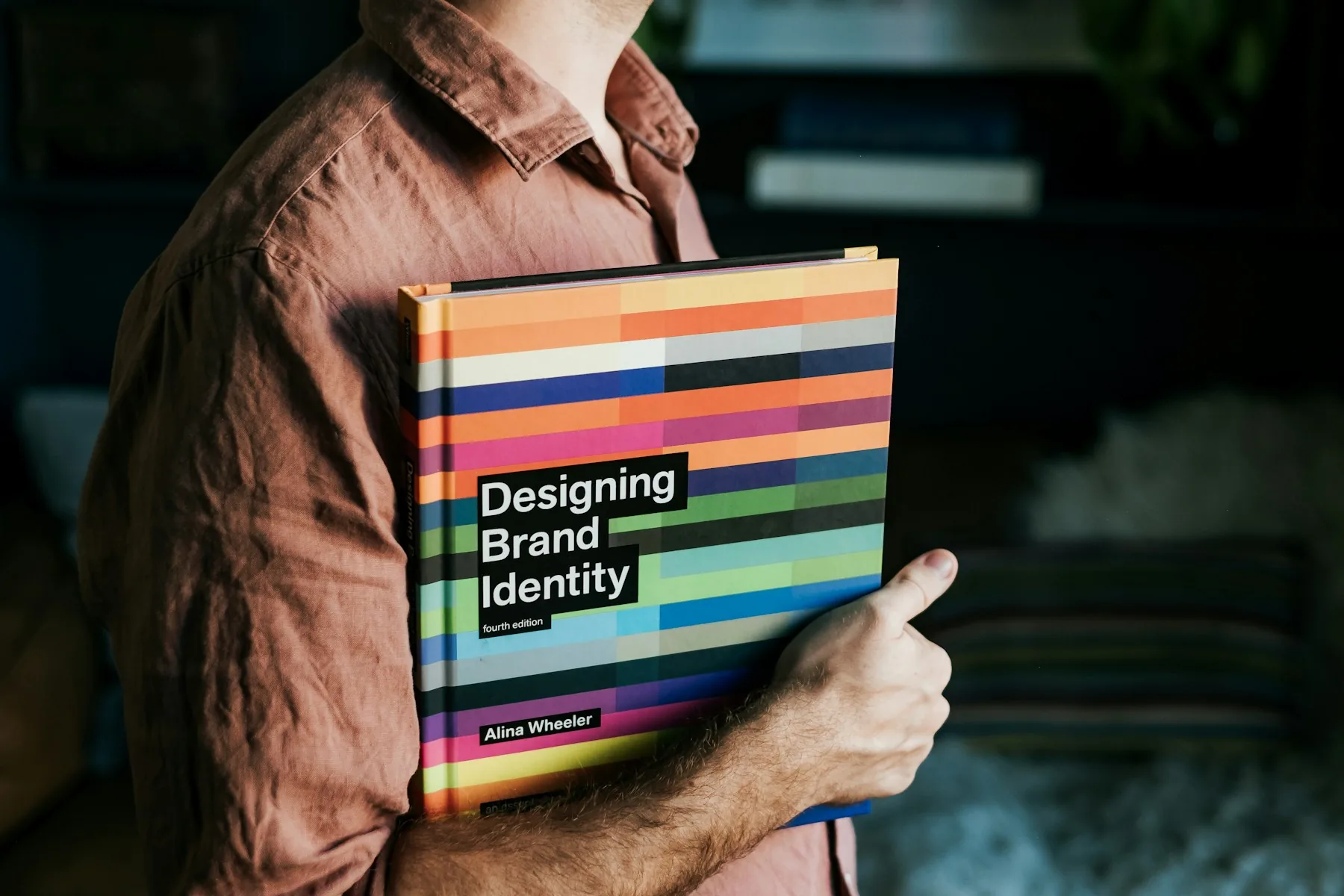 Designer holding a printed brand-identity reference book with colourful typography